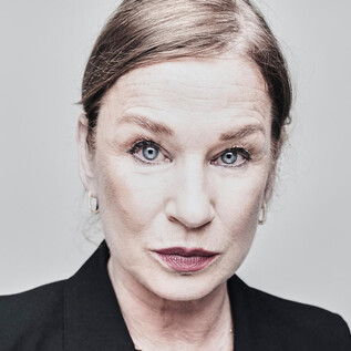 Portrait of a woman with short blond hair and blue eyes. She is wearing a black blazer and has a serious expression. | © Tommy Hetzel