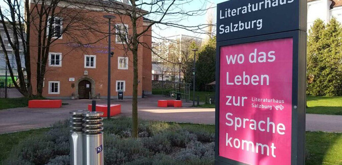 The Literaturhaus Salzburg is a modern building with an inviting outdoor area. Next to the main office, there is an information board with the saying "where life comes to speech." | © Literaturhaus Salzburg