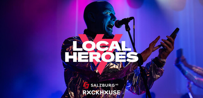 An artist performs on stage and sings into a microphone. Colorful lights are visible in the background, creating a festive atmosphere. | © Rockhouse Salzburg