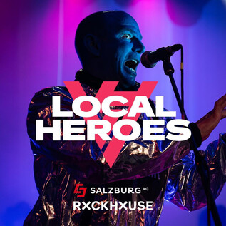 An artist performs on stage and sings into a microphone. Colorful lights are visible in the background, creating a festive atmosphere. | © Rockhouse Salzburg