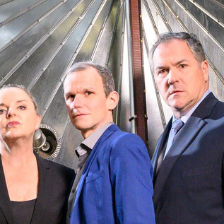 Three people are standing in front of a large, silver structure. The atmosphere is modern and professional. | © SLT / Tobias Witzgall