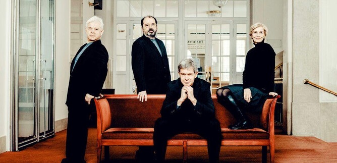 A four-person group of people stands and sits on a sofa in a modern interior. All are dressed in black clothing and are looking at the camera. | © Andrej Grilc