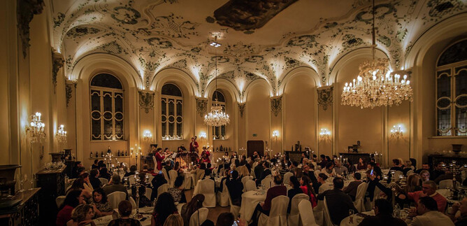 An elegant event space with tastefully decorated tables. Guests enjoy a festive dinner under crystal chandeliers. | © Michael Groessinger