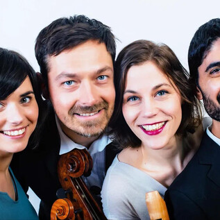 A group of four musicians smiles at the camera. They hold instruments and look friendly. | © Wolfram Knelangen