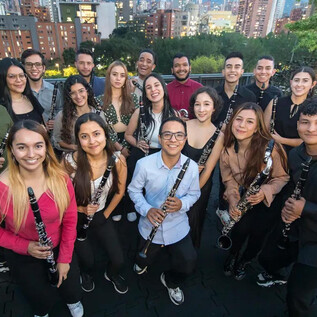 A group of young musicians stands together for a photo. They hold clarinets and smile against an urban backdrop. | © Daniel Romero_Iberacademy
