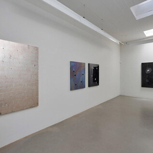 A modern art gallery with four large-format paintings on the wall. The images vary in color and texture, on a gray floor. | © Galerie Frey