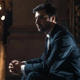 A thoughtful man in an elegant suit is sitting in a stylish place. The light creates a special atmosphere in the background. | © James Orford