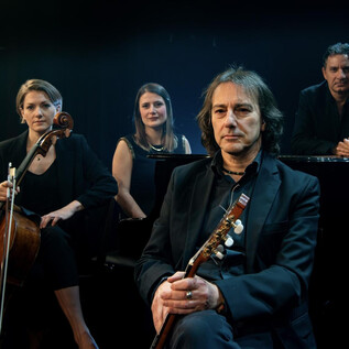 A group of four musicians poses on stage. They play different instruments and exude a creative atmosphere. | © Pippo Pollina | Konzertphotograph