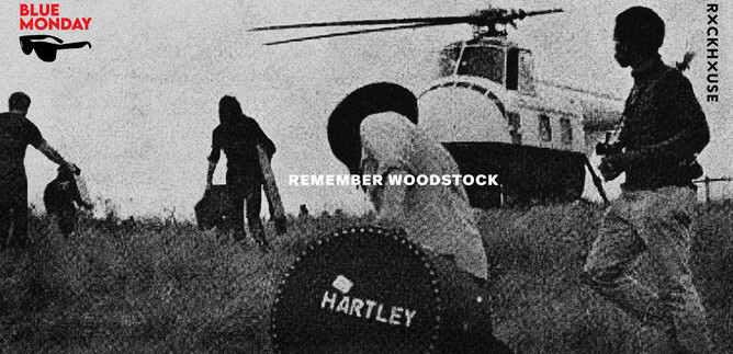 A group of people is moving in a field while a helicopter hovers in the background. In the center of the scene, there is a large suitcase with the inscription "HARTLEY." | © Rockhouse Salzburg