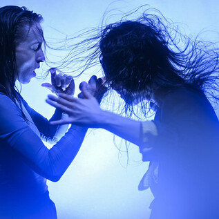 Two women are fighting in a blue light. Their hair is wet and moves dynamically in the water. | © Bernhard Müller