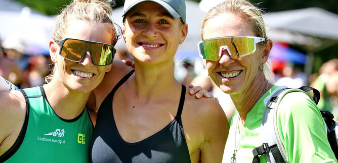 Three athletic women are smiling together at the camera. They are wearing sunglasses and are dressed in sporty clothing. | © Sepp Kühnhold