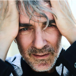 A man with gray hair holds his hands to his face. He looks thoughtful and tense. | © Julian Baumann