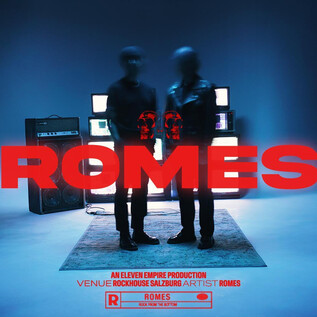 Two silhouette-like figures stand in front of several screens in a blue room. The text "ROMES" is highlighted in red. | © Rockhouse Salzburg