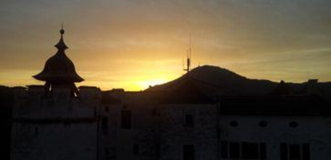 Egy történelmi konyha régi főzőedényekkel és egy kő kandallóval. A padló nagy kövekből készült, és különböző fazekak és kannák találhatók. | © Festung Hohensalzburg