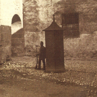 A historic kitchen with old cooking utensils and a stone fireplace. The floor is made of large stones, and there are various pots and jugs. | © Festung Hohensalzburg