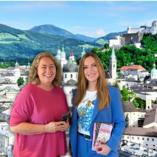 Two women stand in front of a picturesque city view with mountains in the background. The city has historic buildings and landmarks. | © Sabine Rath