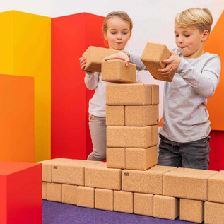 Two children are building a structure with wooden blocks. Colorful geometric shapes are visible in the background. | © Salzburg Museum