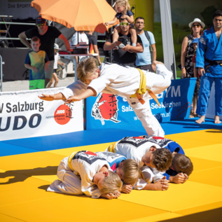 Judo představení na matraci s několika mladými zápasníky. Athlet skáče přes svého tréninkového partnera a předvádí působivou techniku. | © Wild + Team Fotoagentur GmbH