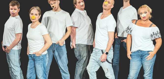 A group of eight people stands in a row, dressed in white T-shirts and jeans. Their faces are creatively painted, enhancing their expressive poses. | © Taro Ebihara