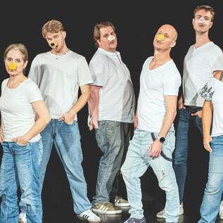 A group of eight people stands in a row, dressed in white T-shirts and jeans. Their faces are creatively painted, enhancing their expressive poses. | © Taro Ebihara