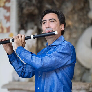 Ein Mann spielt Flöte in einer eleganten Umgebung. Er trägt ein blaues Hemd und konzentriert sich auf die Musik. | © Michael Brauer