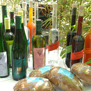 A selection of bottles with various drinks is placed on a table. In the foreground, some flatbread-like products are visible. | © Stadt Salzburg