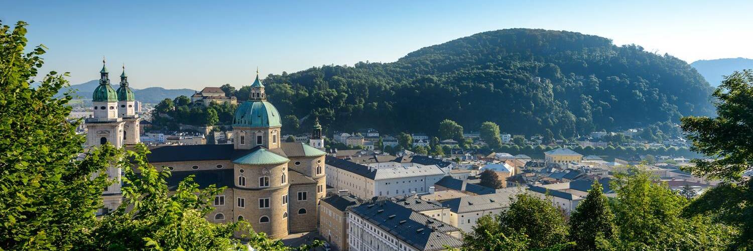 A beautiful city view with historical buildings and hills in the background. The clear sky and the green nature give the scene a serene impression. | © Tourismus Salzburg / G.Breitegger