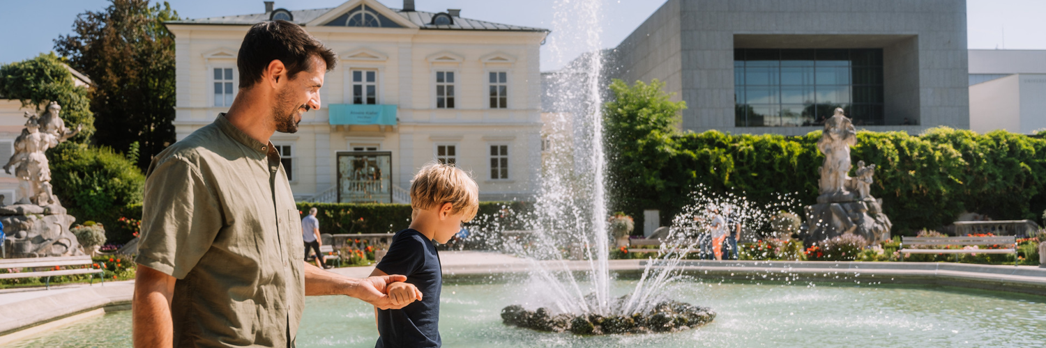 Foto von einem Vater und Sohn am Brunnen im Mirabellgarten. | © Tourismus Salzburg Gmbh / M. Kohlmayr